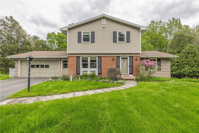 colonial house with a garage, asphalt driveway, a front lawn, and brick siding