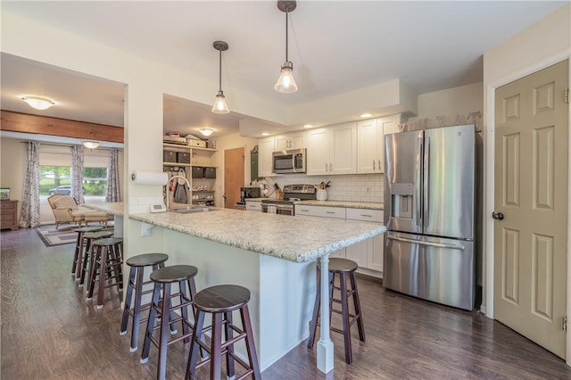 kitchen with stainless steel appliances, a sink, a kitchen breakfast bar, and white cabinetry