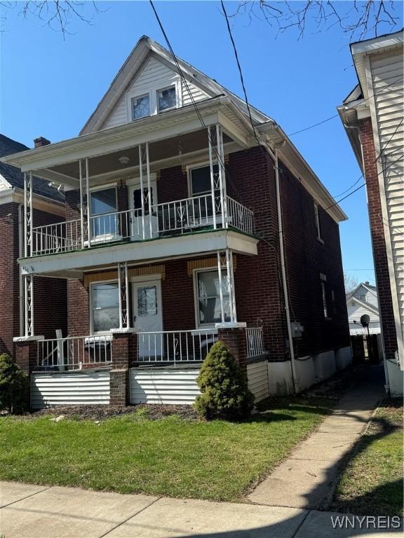 view of front of house featuring a balcony, a porch, and brick siding