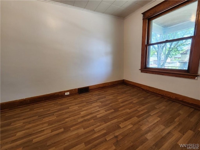 empty room with baseboards, dark wood-style flooring, and crown molding