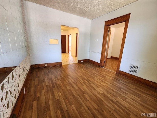 spare room featuring wood finished floors, baseboards, and a textured ceiling