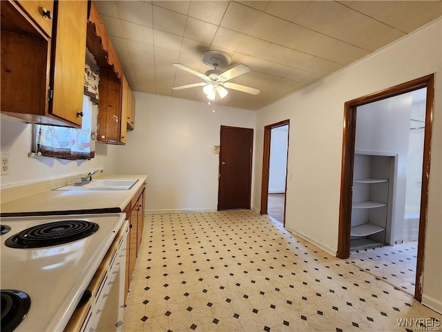 kitchen with a sink, light flooring, ceiling fan, electric stove, and brown cabinetry