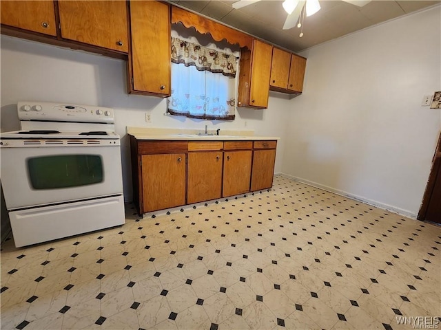 kitchen with white range with electric stovetop, brown cabinetry, light countertops, ceiling fan, and light flooring