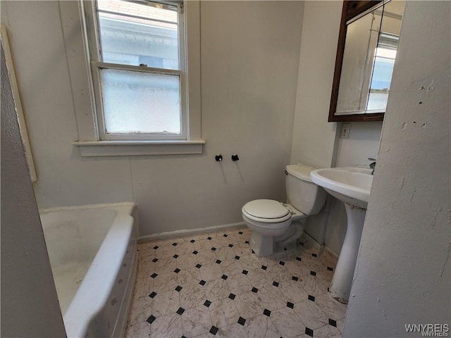 full bathroom with tile patterned floors, toilet, a tub to relax in, and baseboards