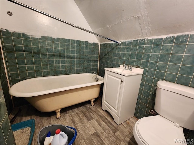 full bathroom with tile walls, wood finished floors, toilet, a tub, and lofted ceiling