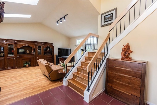 401 Montvale Ln, Greece, NY 14626 - stairway featuring vaulted ceiling, a skylight, tile patterned floors, rail lighting, and baseboards
