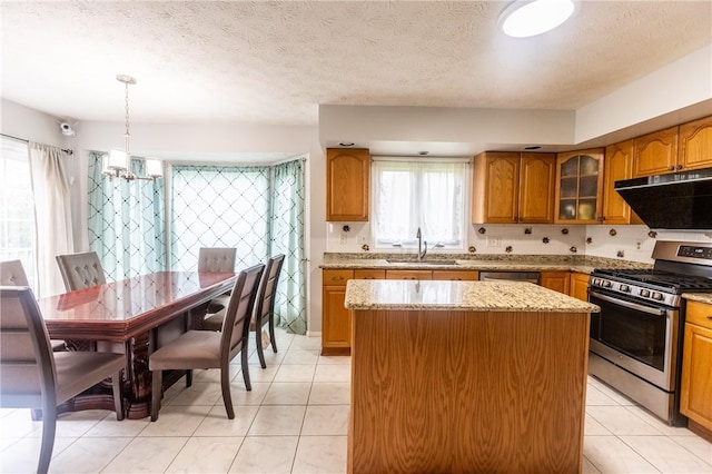 401 Montvale Ln, Greece, NY 14626 - kitchen with stainless steel appliances, under cabinet range hood, a sink, brown cabinetry, and a kitchen island
