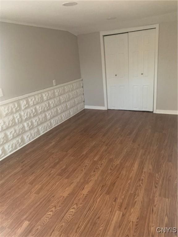 unfurnished bedroom featuring wood finished floors, a closet, and baseboards