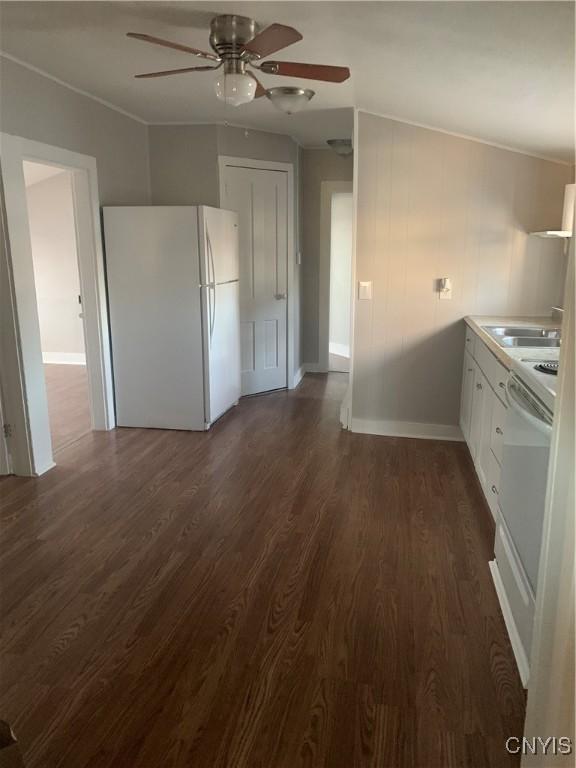 kitchen with freestanding refrigerator, a ceiling fan, dark wood-style flooring, baseboards, and white cabinets