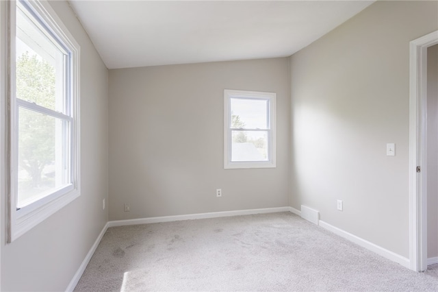 empty room featuring light colored carpet, baseboards, and vaulted ceiling