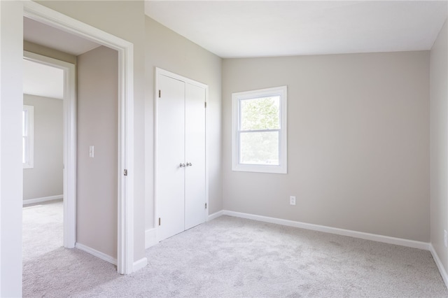 unfurnished bedroom featuring light colored carpet and baseboards