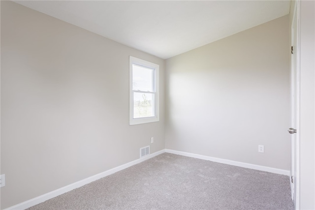 spare room featuring carpet floors, baseboards, and lofted ceiling