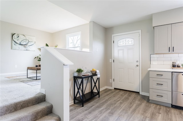 foyer with light wood-type flooring, baseboards, and stairs