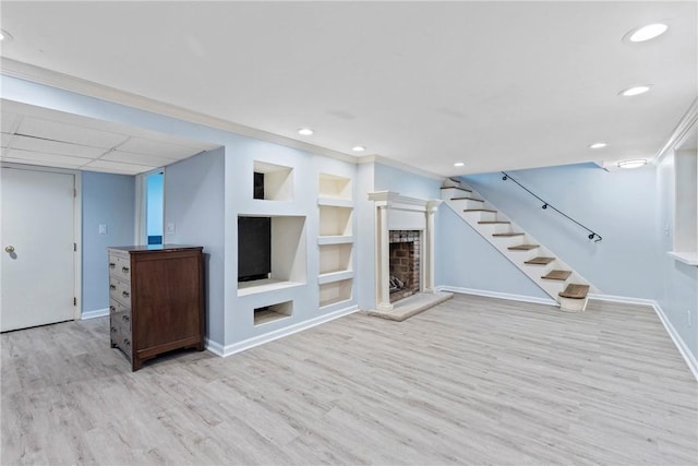 unfurnished living room featuring wood finished floors, a fireplace with raised hearth, baseboards, built in shelves, and recessed lighting