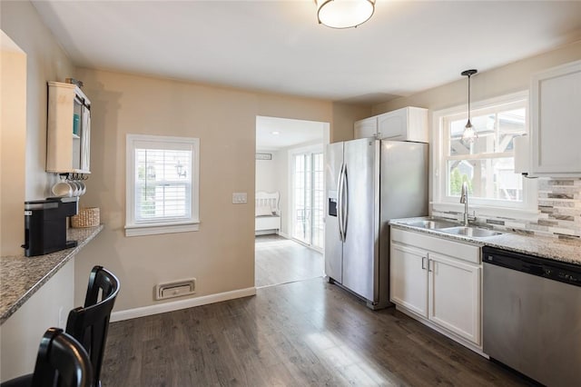 kitchen featuring stainless steel appliances, a sink, dark wood-style flooring, white cabinetry, and healthy amount of natural light