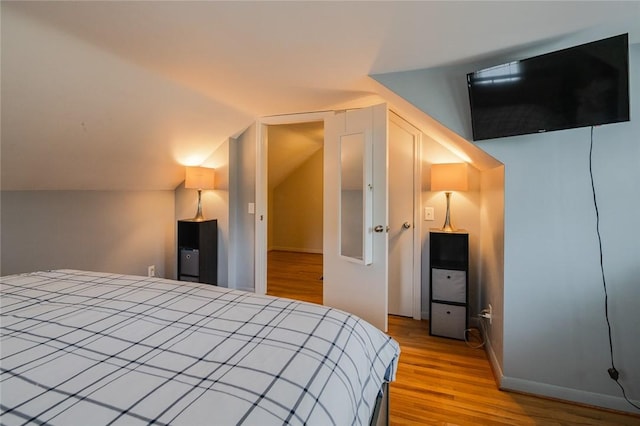 bedroom with light wood-style floors and vaulted ceiling