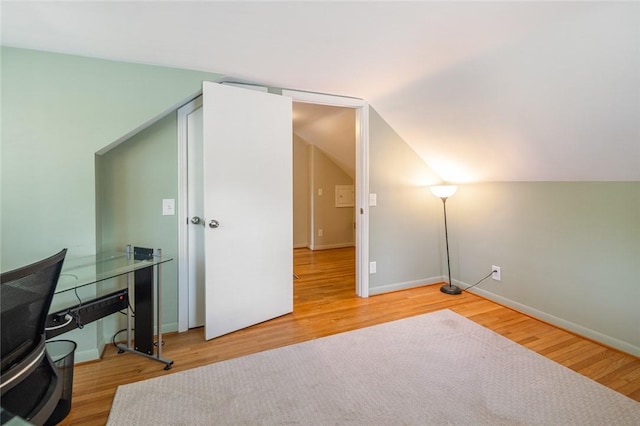 unfurnished office with wood finished floors, vaulted ceiling, and baseboards