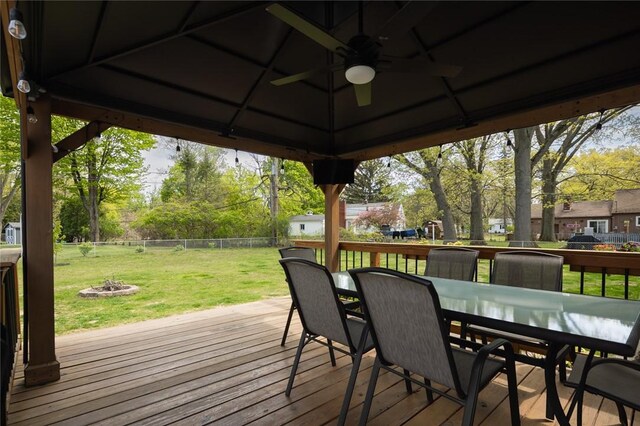 deck with ceiling fan, outdoor dining space, a gazebo, and a fire pit