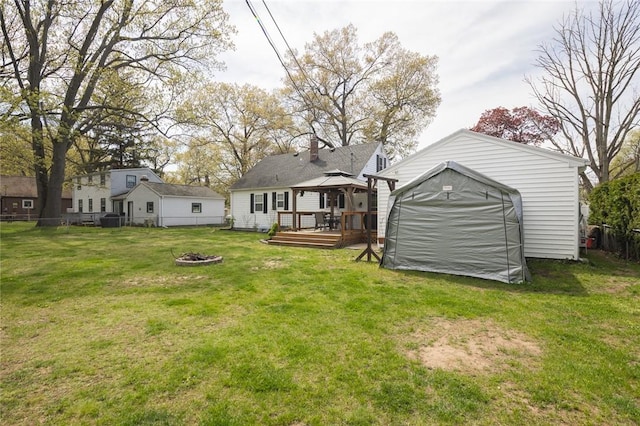 back of house with a gazebo, a fire pit, a wooden deck, a storage unit, and an outdoor structure