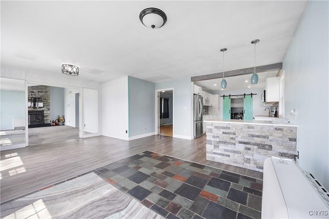 1019 State Route 49, Constantia, NY 13028 - unfurnished living room featuring a barn door, a sink, dark wood-style floors, and baseboards