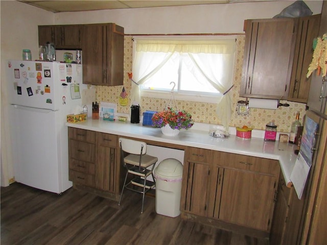 kitchen with freestanding refrigerator, dark wood-style floors, light countertops, and brown cabinets