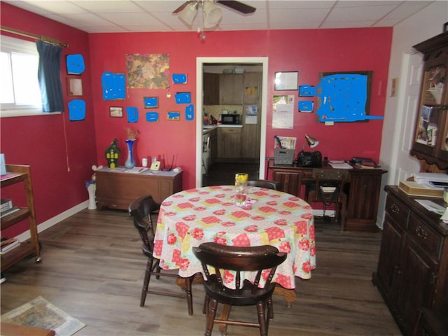 dining space featuring a paneled ceiling, wood finished floors, a ceiling fan, and baseboards