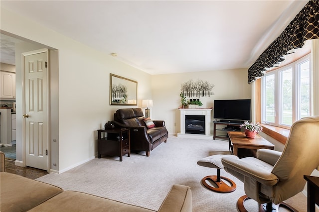 living area with light carpet, a glass covered fireplace, and baseboards