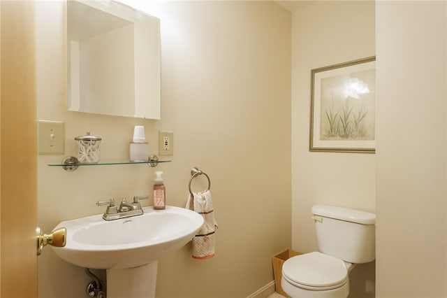 bathroom featuring toilet, a sink, and baseboards