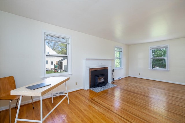 living room with light wood-style floors, baseboards, and a wood stove