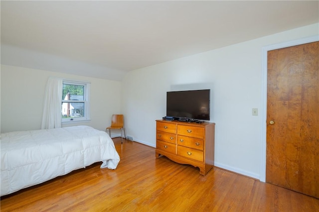 bedroom featuring light wood finished floors and vaulted ceiling
