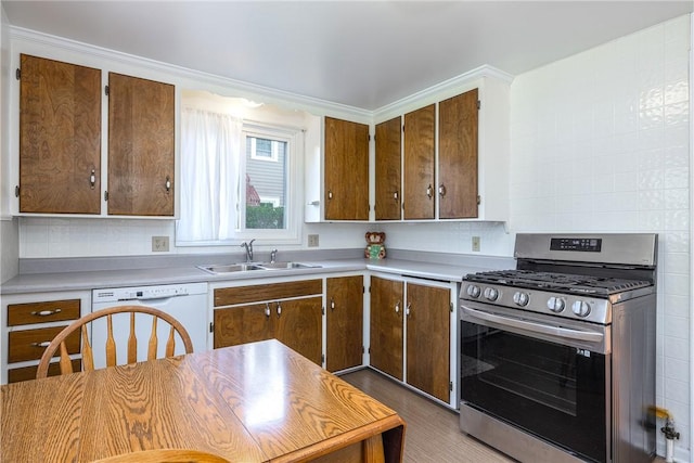 kitchen with stainless steel range with gas stovetop, a sink, light countertops, and tasteful backsplash