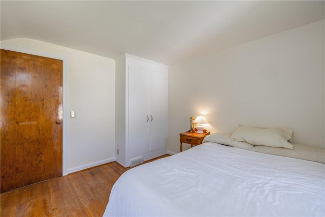 bedroom featuring wood finished floors, baseboards, and a closet