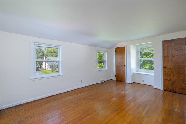 unfurnished bedroom with wood finished floors, vaulted ceiling, multiple closets, and baseboards