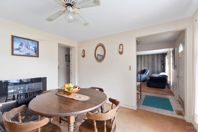 dining space with a ceiling fan, carpet, baseboards, and tile patterned flooring