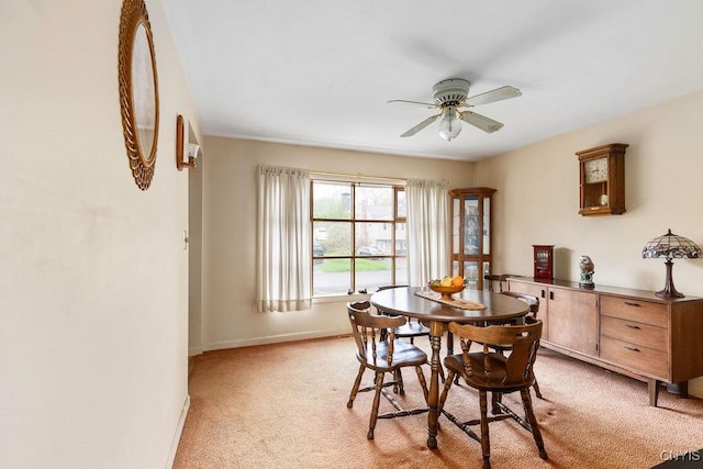 dining space featuring light colored carpet, ceiling fan, and baseboards
