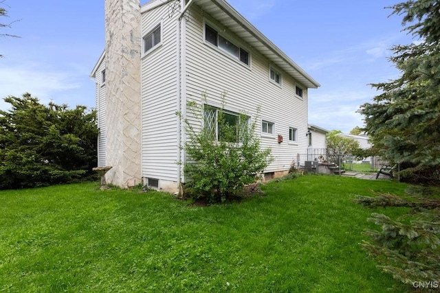 view of property exterior with a chimney, a lawn, and central AC unit