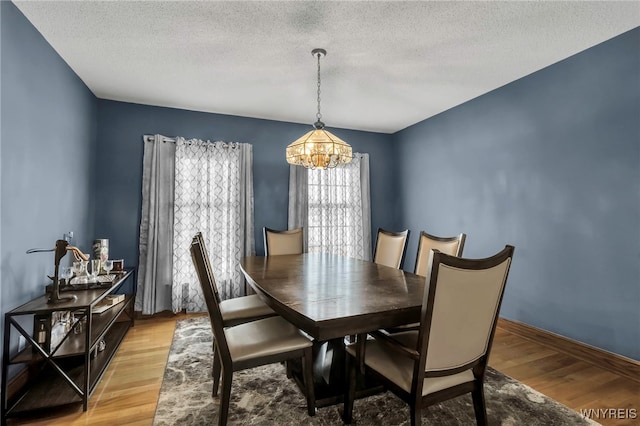 3472 Stevenson Ct, Wheatfield, NY 14120 - dining area featuring a chandelier, light wood finished floors, a textured ceiling, and baseboards