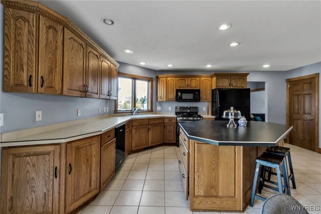 kitchen with black appliances, a center island, brown cabinetry, light tile patterned flooring, and a sink