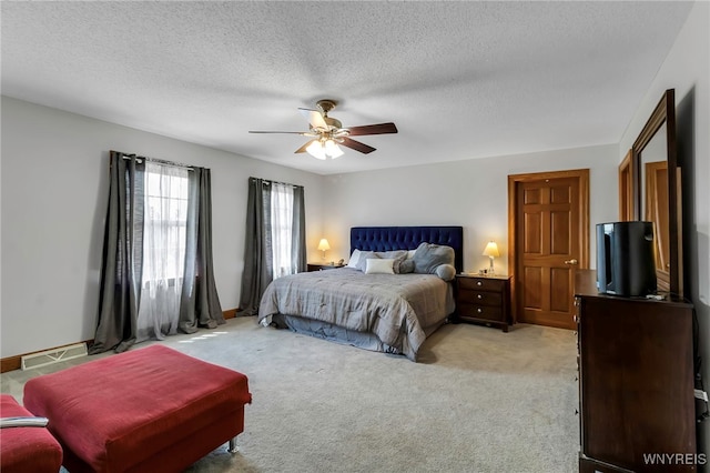 bedroom with light colored carpet, a textured ceiling, and a ceiling fan
