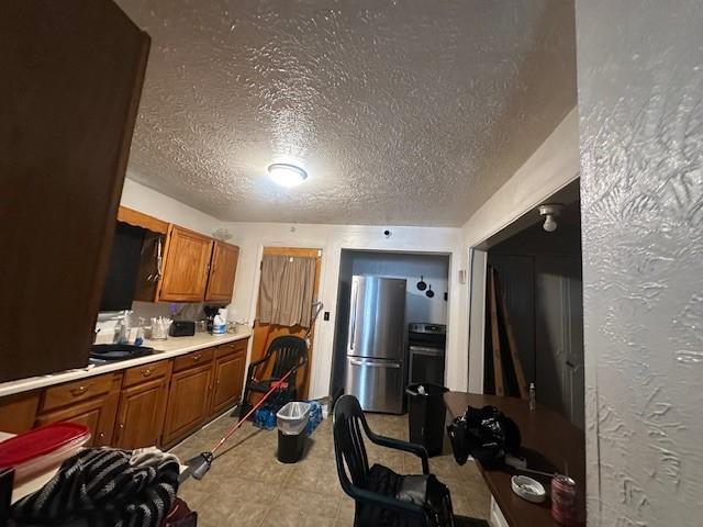 199 Roycroft Dr, Rochester, NY 14621 - kitchen featuring freestanding refrigerator, brown cabinetry, light countertops, a textured ceiling, and a sink
