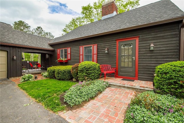 doorway to property featuring a chimney and a shingled roof