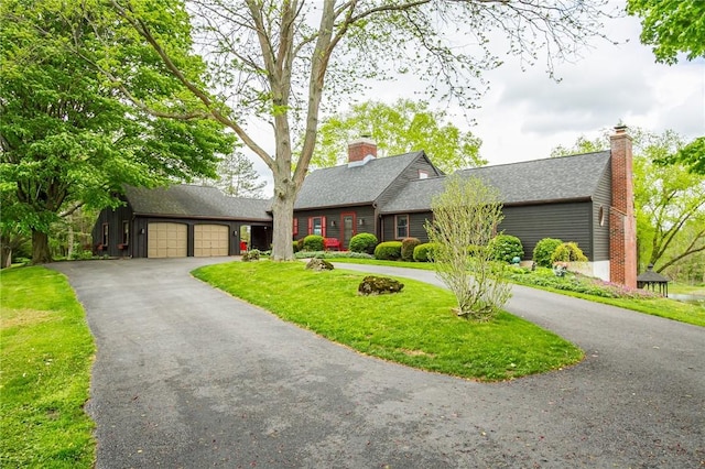 view of front of home with a garage, driveway, a front lawn, and roof with shingles
