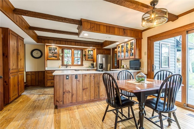 dining room featuring light wood-style flooring, plenty of natural light, a wainscoted wall, and wood walls
