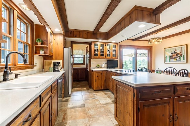 kitchen with a sink, beam ceiling, stainless steel appliances, light countertops, and plenty of natural light