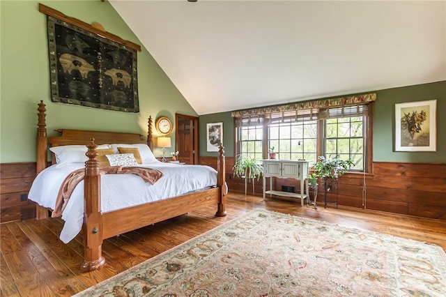 bedroom featuring lofted ceiling, wood finished floors, and wainscoting
