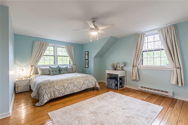 bedroom with a baseboard heating unit, hardwood / wood-style flooring, baseboards, and ceiling fan