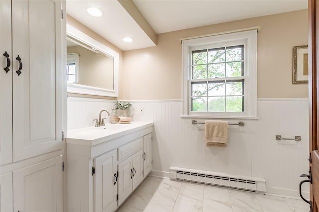 bathroom with baseboard heating, a wainscoted wall, marble look tile flooring, and vanity