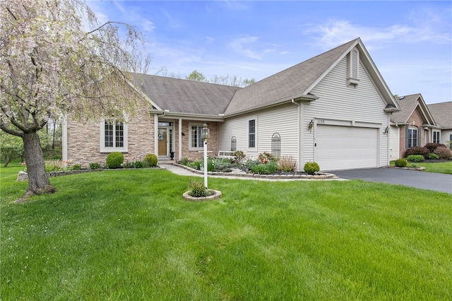 ranch-style house featuring roof with shingles, asphalt driveway, and a front lawn
