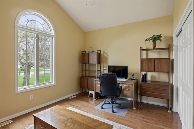 office space with plenty of natural light, vaulted ceiling, light wood-type flooring, and a ceiling fan