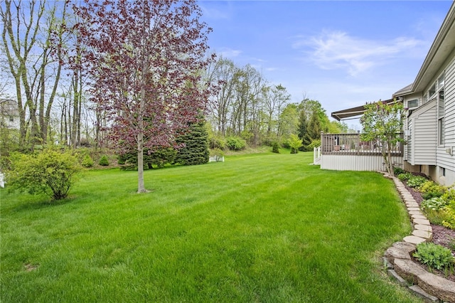 view of green lawn with a wooden deck